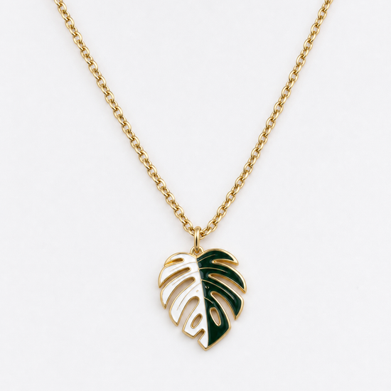 A gold chain necklace featuring a monstera leaf pendant with dark green enamel accents, shown against a plain white background. plant jewelry